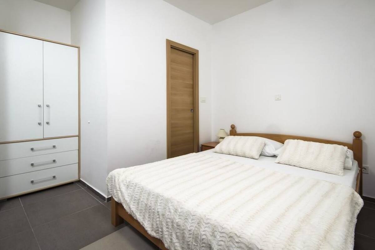 A bedroom with a bed, a wardrobe, and a door.