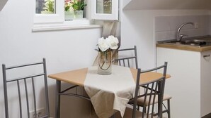 Una cocina pequeña con ventana, una mesa con sillas y un equipo de aire acondicionado.