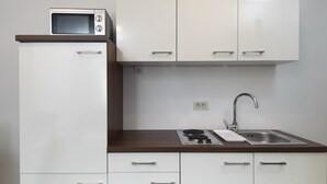 A kitchen with white cabinets, a microwave, a sink, and a stove. - Nera Luxury Apartments (Split)