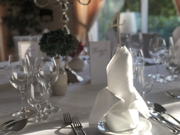 A table set for a formal dining event with clear glassware, folded napkins, and a candle centerpiece.