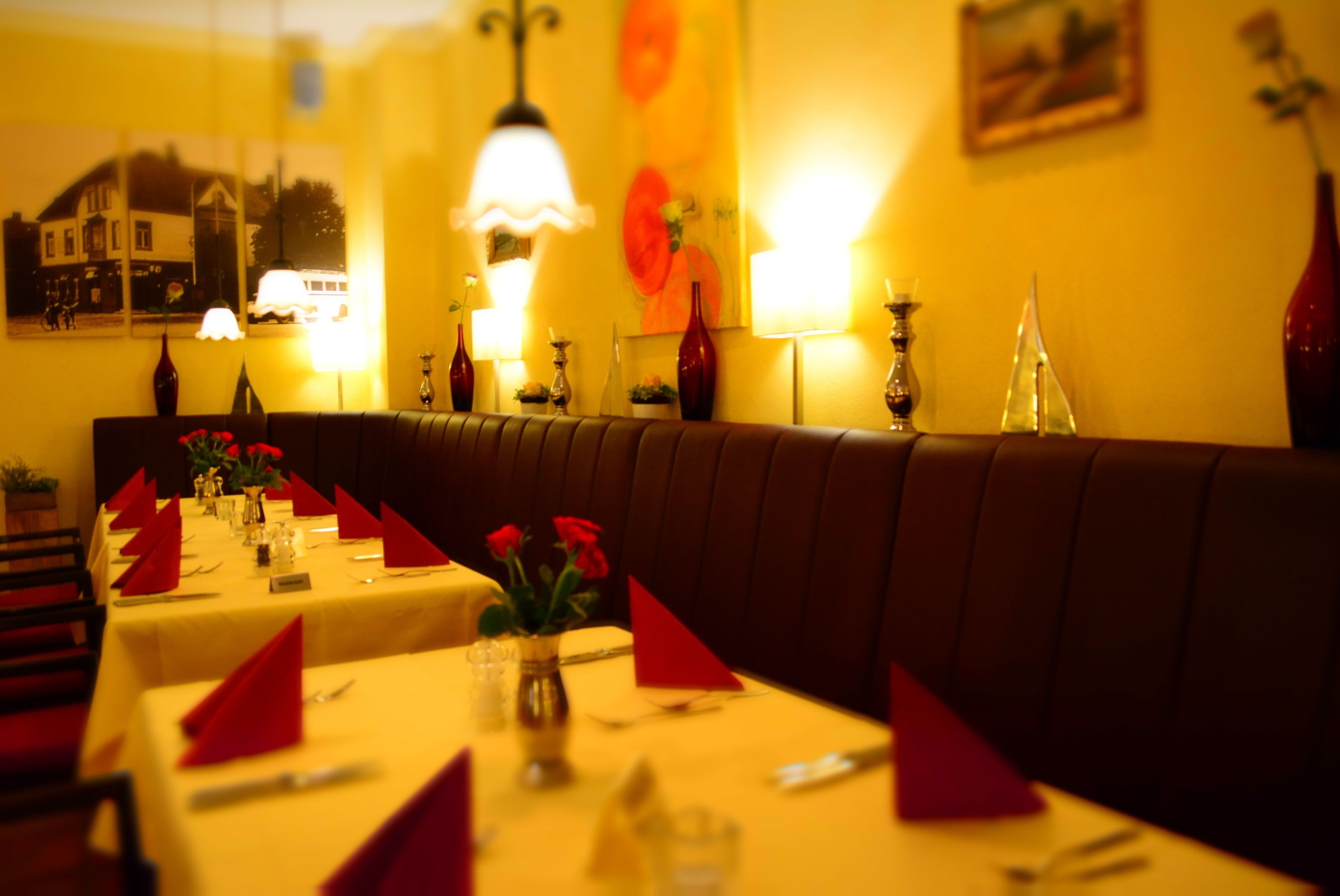 A restaurant with multiple tables set for dining, each with red napkins and cutlery.