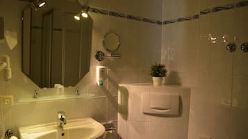 Une salle de bain équipée d’un lavabo, d’un miroir, d’un porte-serviettes et d’une petite plante en pot.