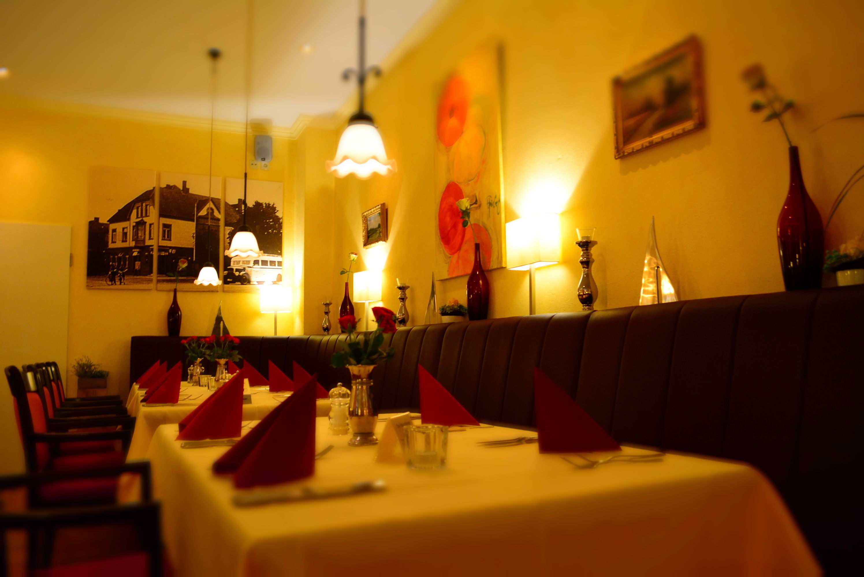 Un restaurant avec un long comptoir, des serviettes rouges et un grand tableau accroché au mur.