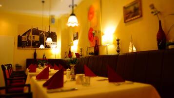 Un restaurante con una barra larga, servilletas rojas y un cuadro grande en la pared.