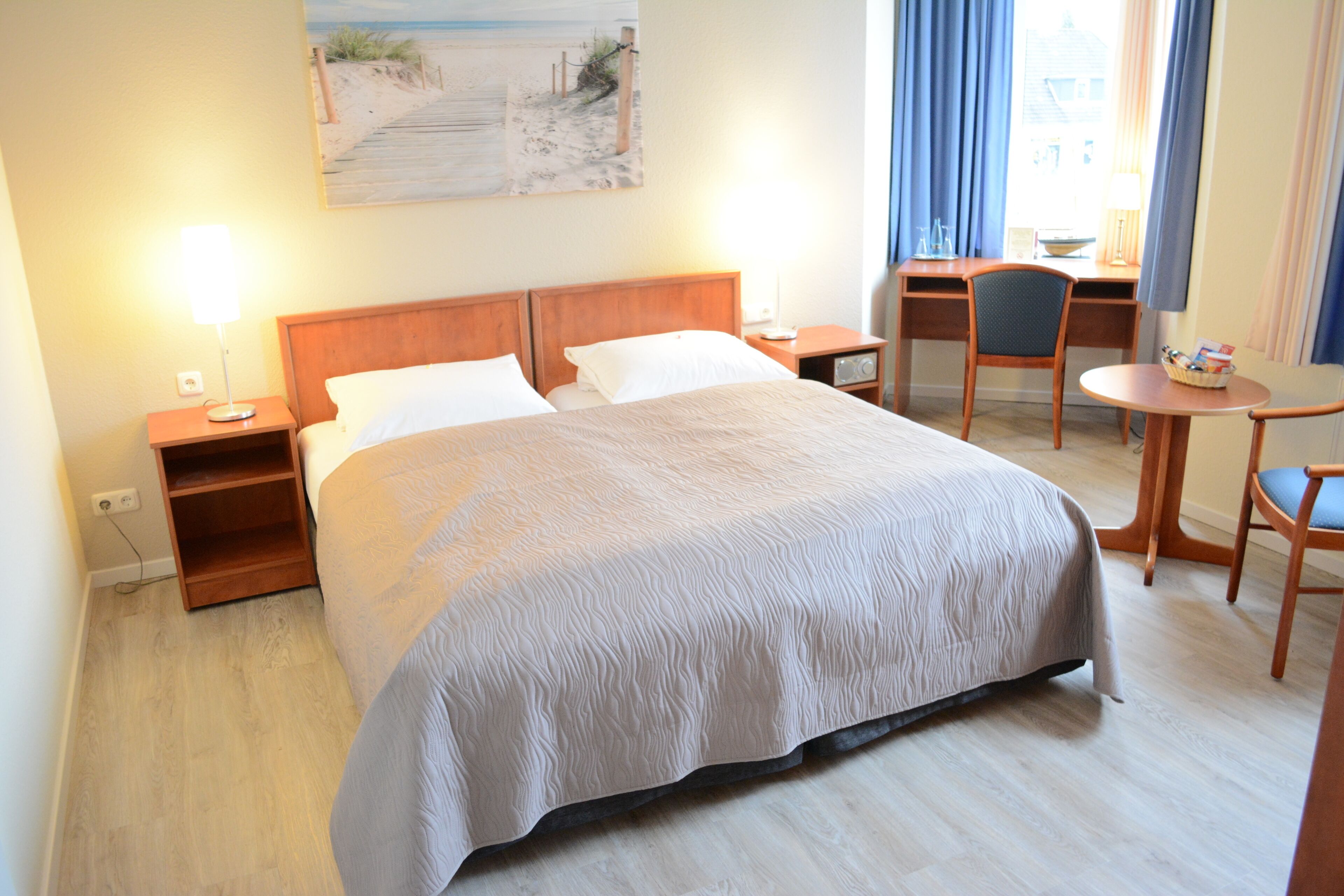 Una habitación de hotel con cama, mesitas de noche, escritorio y una silla.