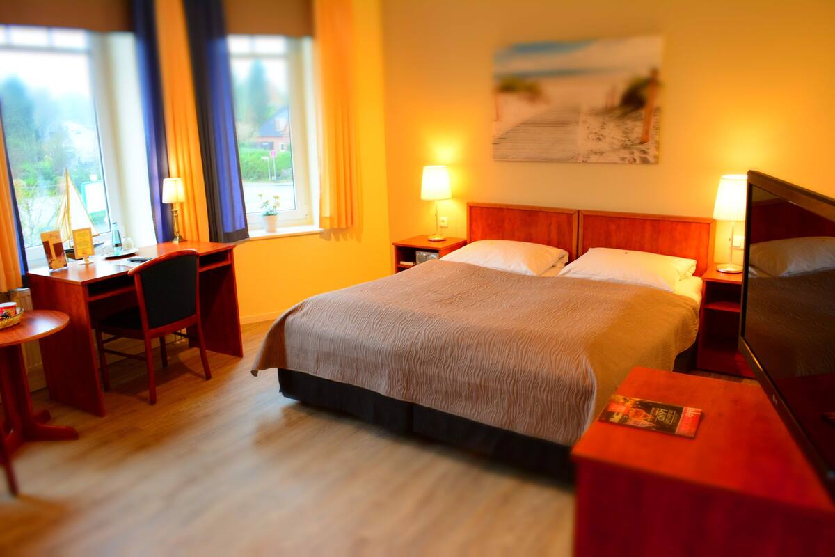 Une chambre d’hôtel comprenant un lit, un bureau, une chaise et deux lampes de chevet.