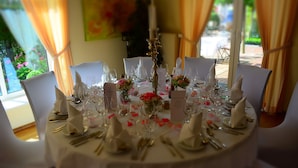 Ein runder Tisch, festlich gedeckt mit weißen Tischdecken, goldartigem Besteck und floralen Mittelpunkten.
