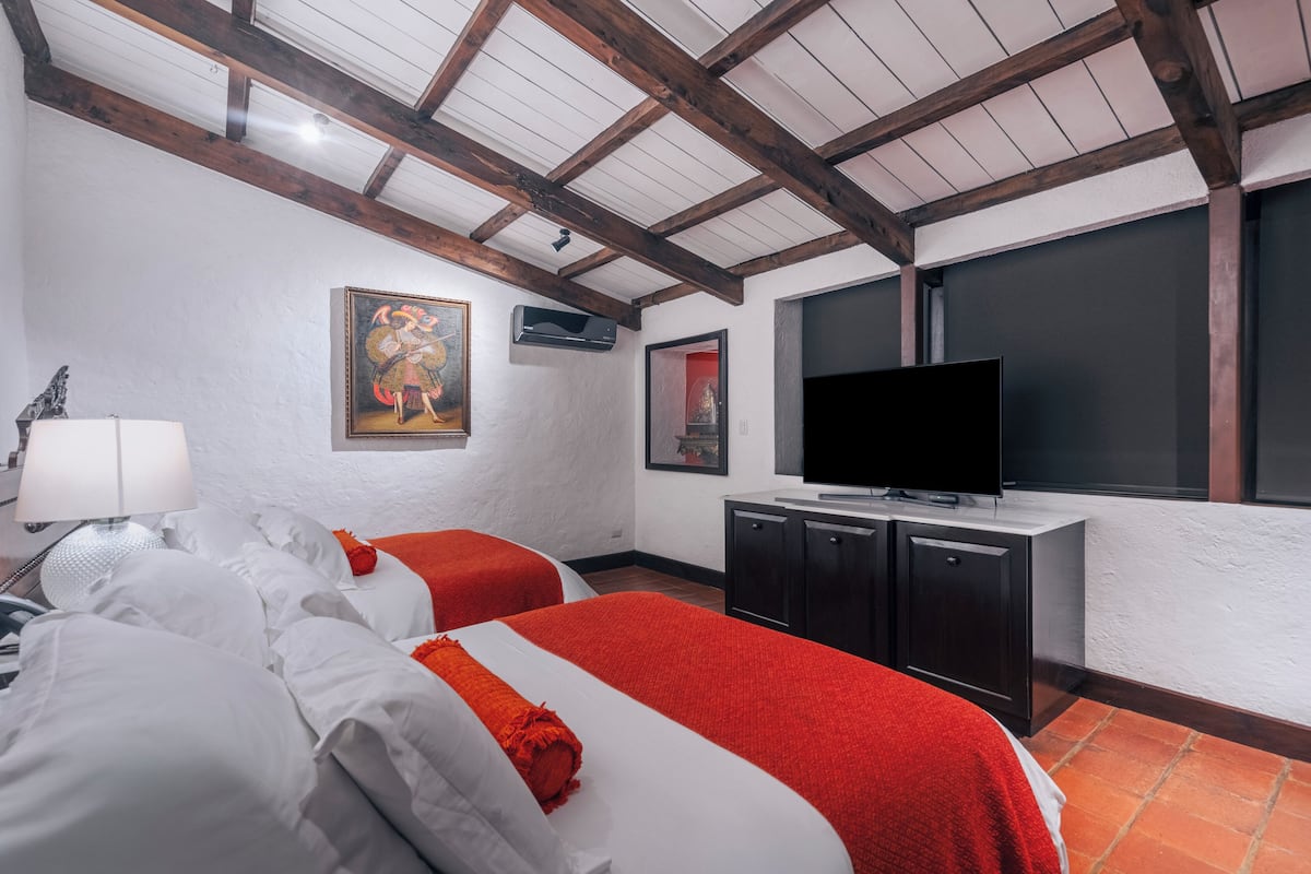 Un dormitorio con dos camas, televisión y obras de arte en la pared.