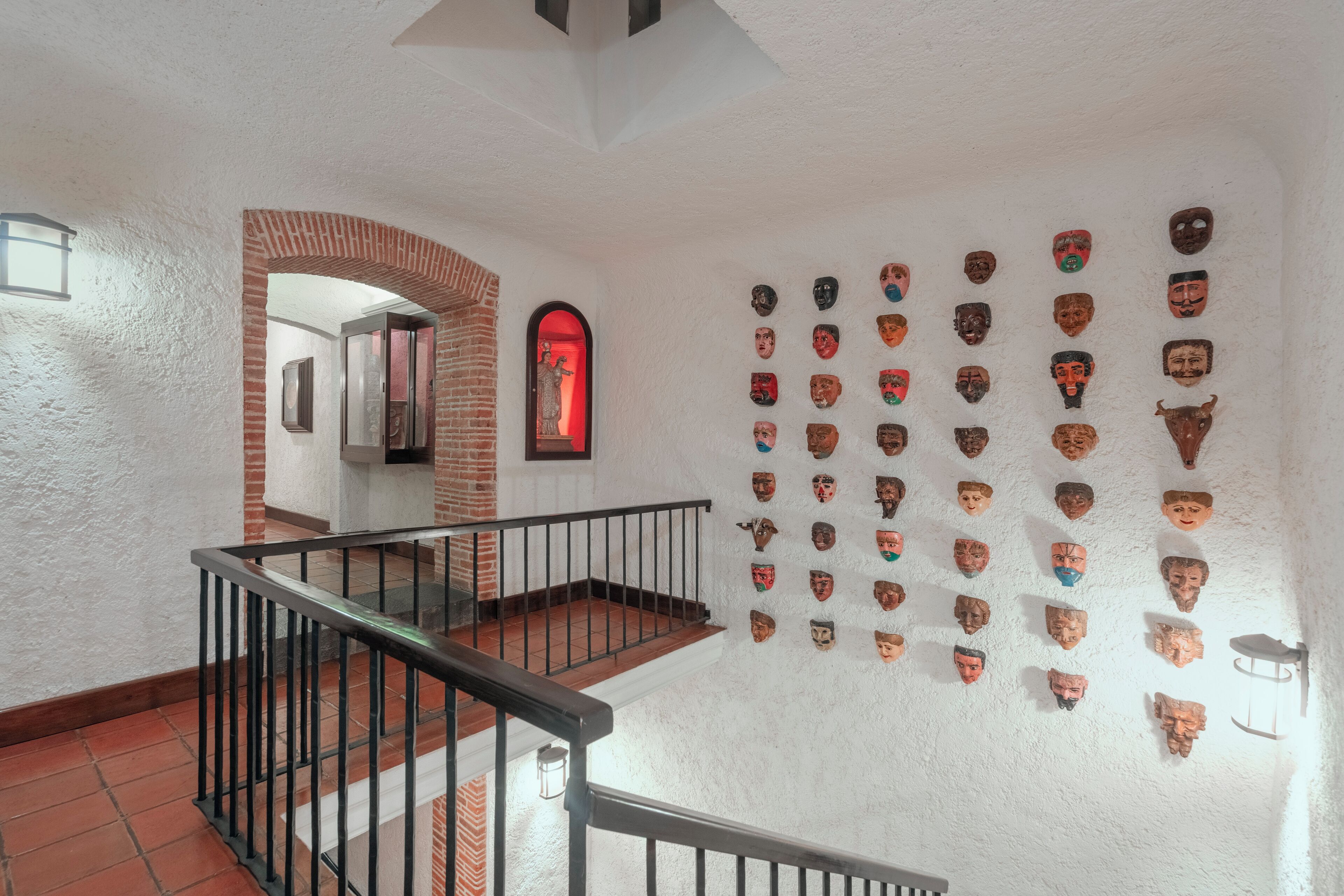 Una escalera con un arco de ladrillo que conduce a una habitación con una puerta iluminada en rojo.