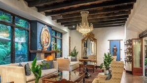 A spacious living room with a large window, a chandelier, and a statue.