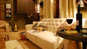 Una sala de estar acogedora con un sofá blanco, una pared de piedra, un aparador de madera y una lámpara.