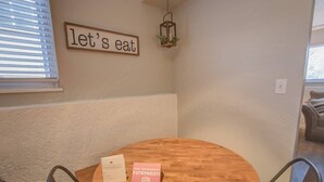 A dining area with a round wooden table, a sign that says "let's eat," and a small sign encouraging guests to share their experience on Instagram. - Steps to Red Rocks Trails by Old Colorado City Pad (Colorado Springs)