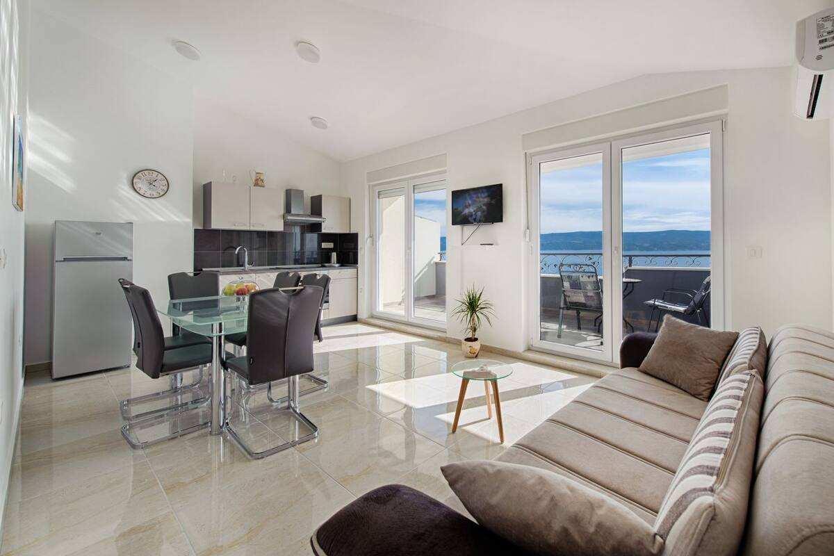 A modern apartment with a kitchen, dining area, and living room with a balcony.