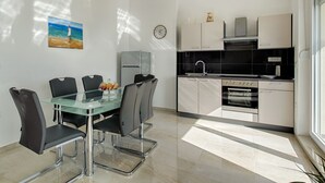 A modern kitchen with a black countertop, stainless steel appliances, and a white cabinet. - Cezar Luxury Apartments (Omis)