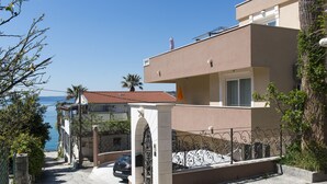 Un edificio costero con balcón, un camino de piedra y vistas al mar.