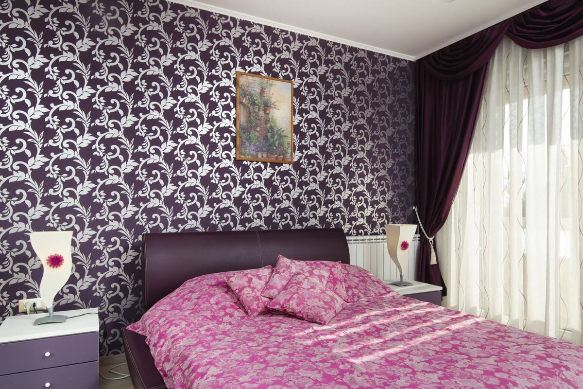 Une chambre à coucher avec un lit, des tables de chevet, une lampe et une fenêtre avec des rideaux.