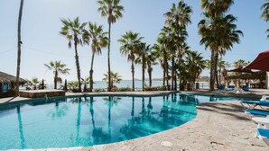 A swimming pool with clear blue water, surrounded by palm trees and lounge chairs. - Hotel Rancho Buena Vista (Buenavista)