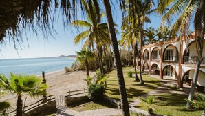 A coastal property with a beach, palm trees, and a building with arched windows. - Hotel Rancho Buena Vista (Buenavista)