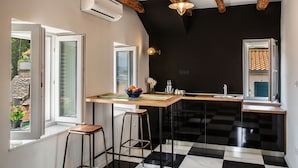 Una cocina moderna con piso a cuadros blanco y negro, taburetes de bar de madera, barra de madera y una lámpara colgante.