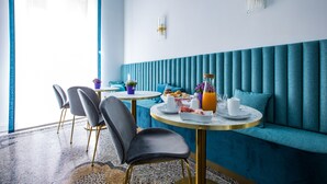 A modern dining area with a blue upholstered bench, round tables, and chairs. - Hold Rome (Rome)