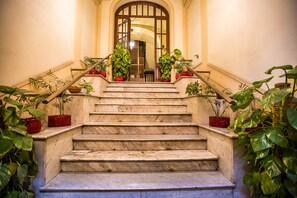 A marble staircase with potted plants on the sides leading to a door with a glass panel. - Hold Rome (Rome)
