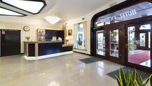 Un hall d’hôtel comprenant un comptoir d’accueil, une horloge et un lustre.