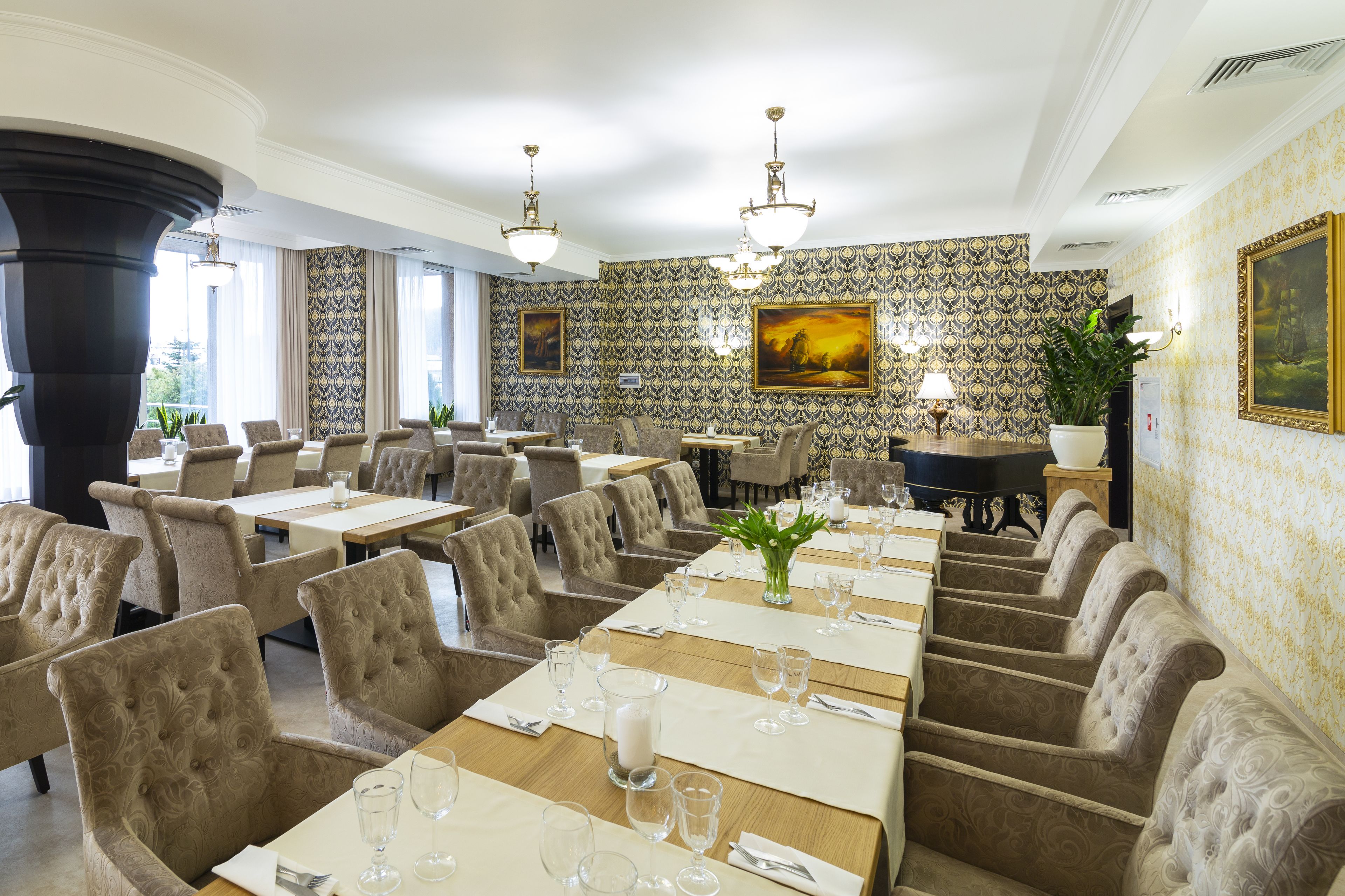A dining area with multiple tables set for service, upholstered chairs, and decorative wall patterns.