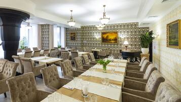 A dining area with multiple tables set for service, upholstered chairs, and decorative wall patterns.