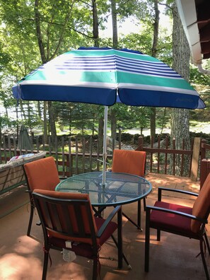 A round metal table with four chairs, an umbrella, and a hammock in a wooded outdoor area. - Vintage 1950's Lakefront Cabin  Private Dock, Sunrise Views & Pet Friendly (Lakeville)
