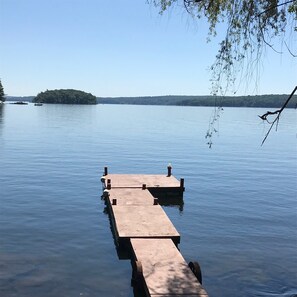 A wooden dock extending into calm water with a clear sky and a distant island. - Vintage 1950's Lakefront Cabin  Private Dock, Sunrise Views & Pet Friendly (Lakeville)