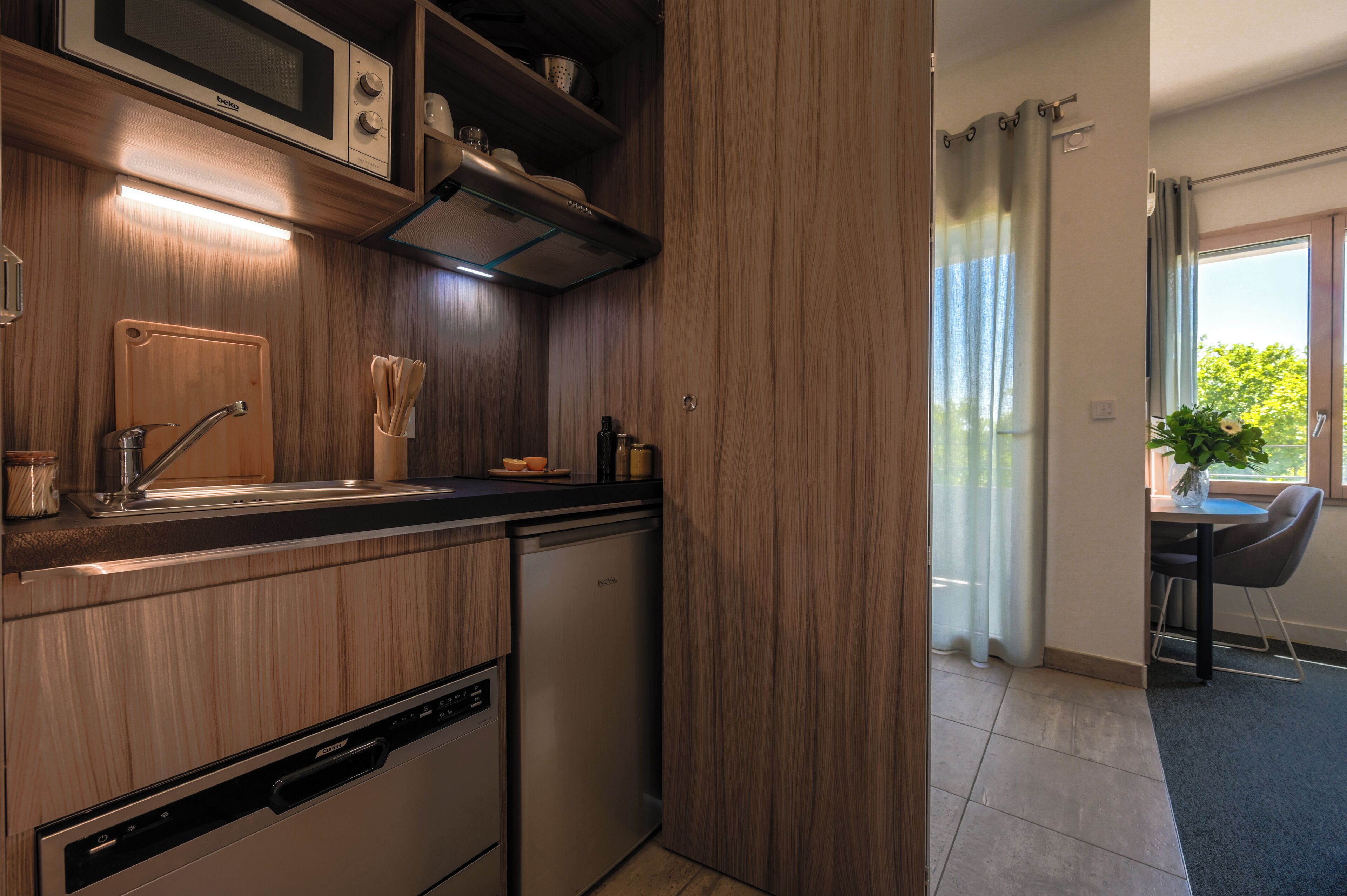 Une cuisine moderne avec des meubles en bois, un four à micro-ondes encastré et un lave-vaisselle.