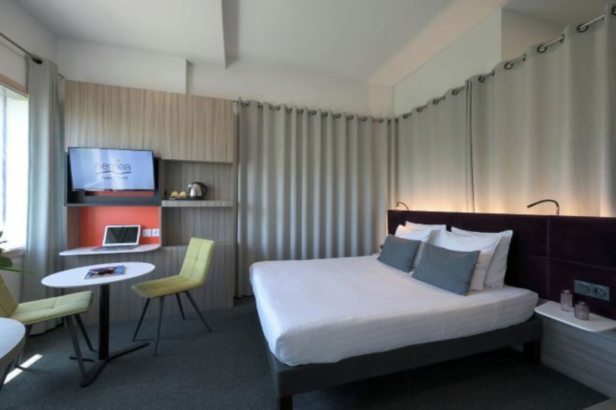 Una habitación de hotel moderna con cama, escritorio, silla y televisión.