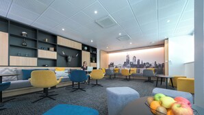 A modern lounge area with seating, a cityscape mural, and a fruit bowl on a table. - Nemea Appart Hotel So Cloud Lyon Part Dieu (Lyon)