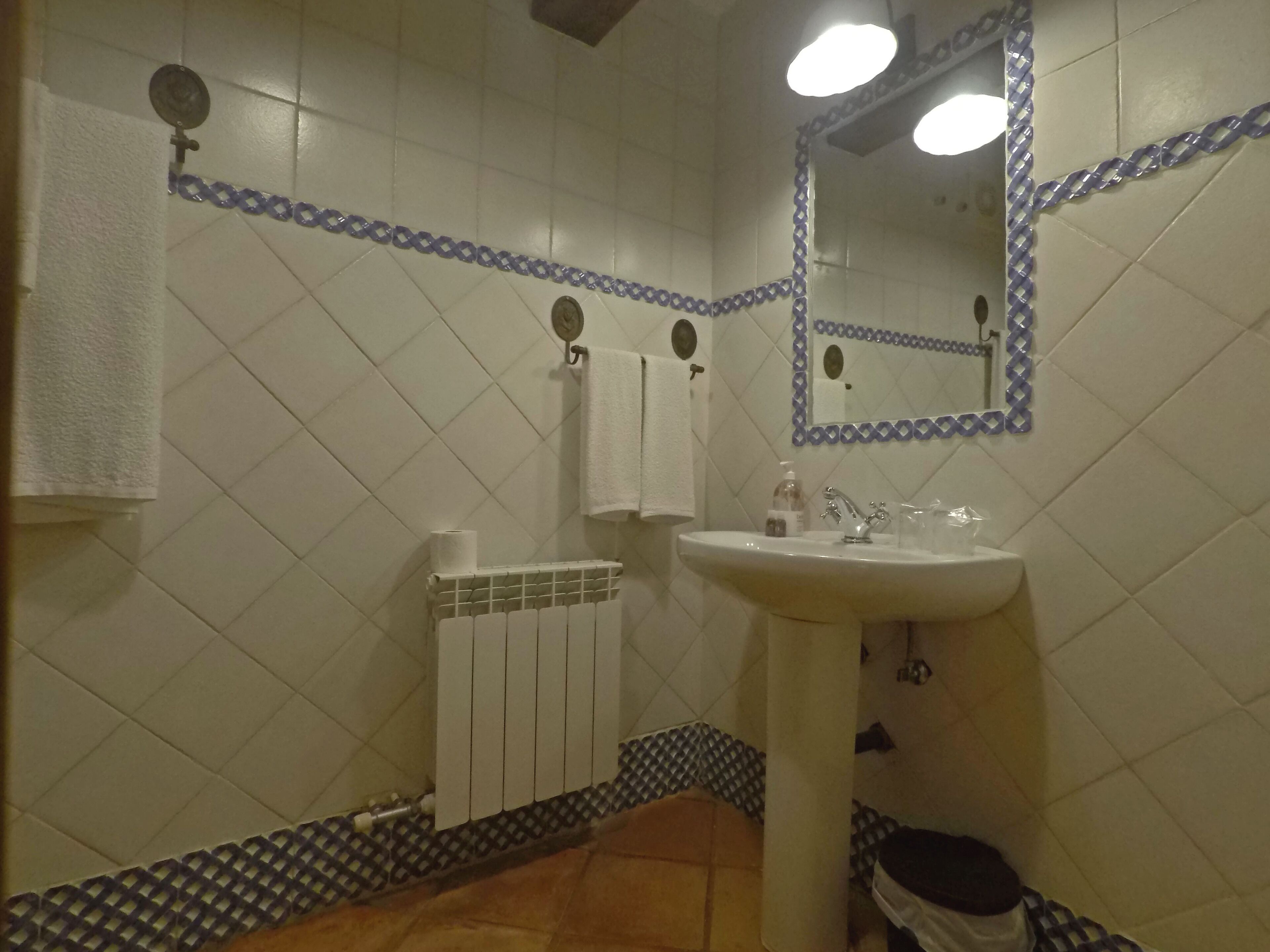 Un baño con un lavamanos blanco, un espejo y un toallero.