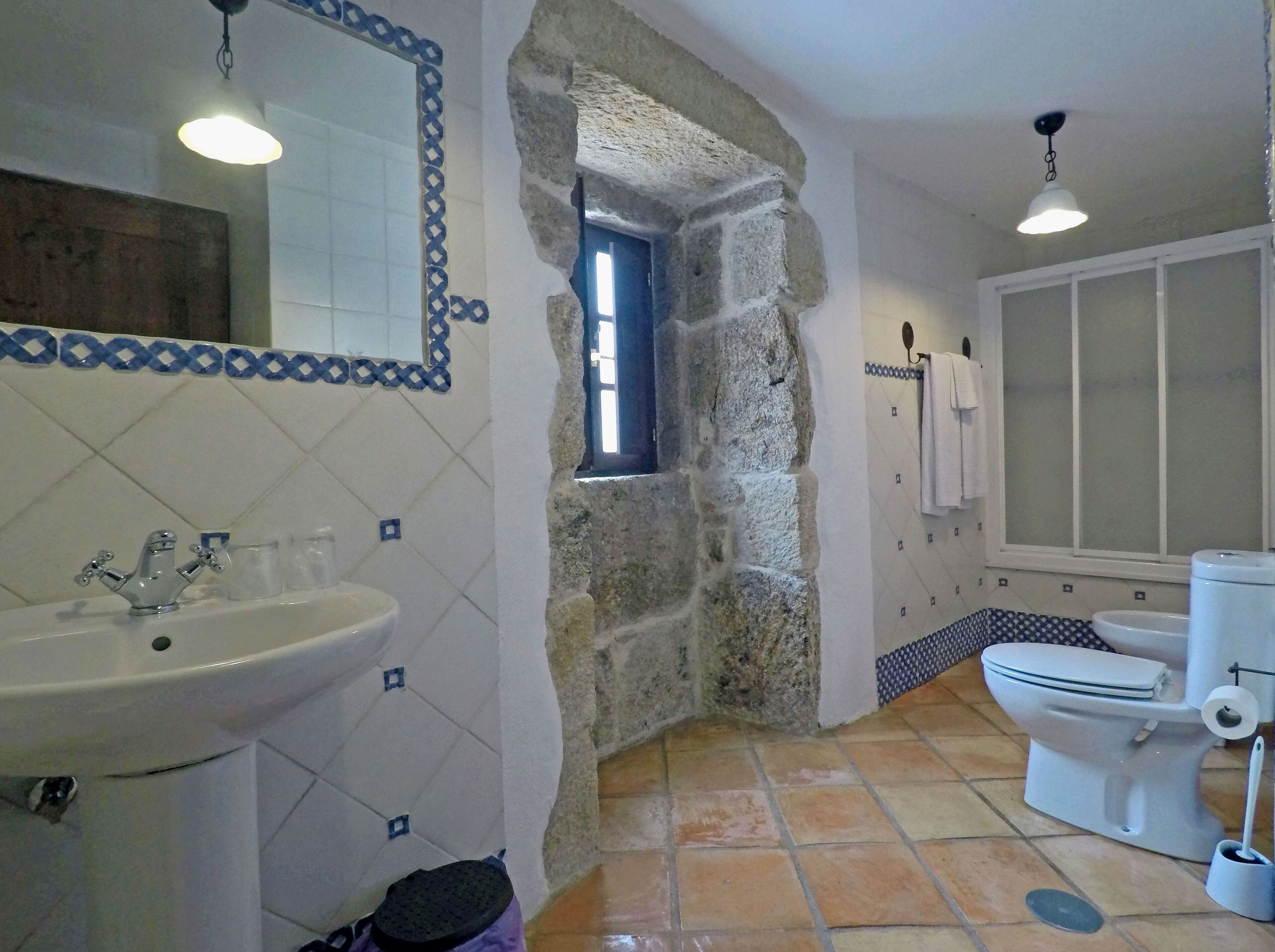 A bathroom with a stone archway, a sink, a toilet, and a mirror.