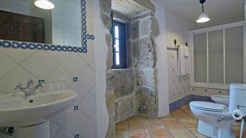 A bathroom with a stone archway, a sink, a toilet, and a mirror.