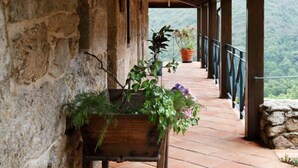 A covered outdoor area with stone walls, wooden beams, and potted plants. - Lugar Dos Devas (Covelo)