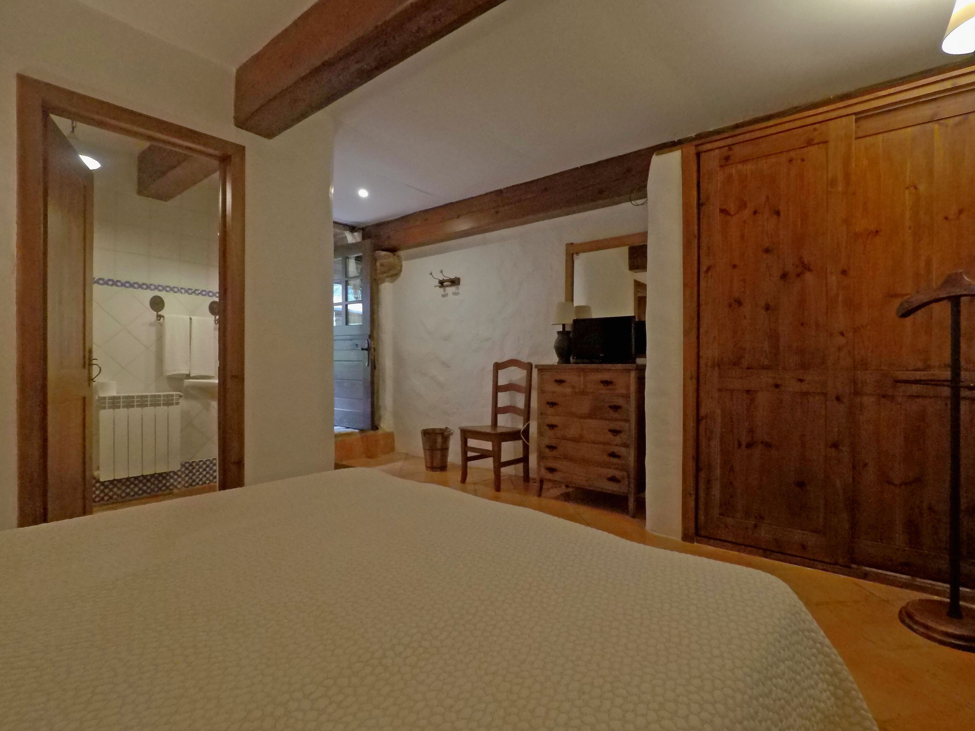 Un dormitorio con cama, cómoda de madera y armario.