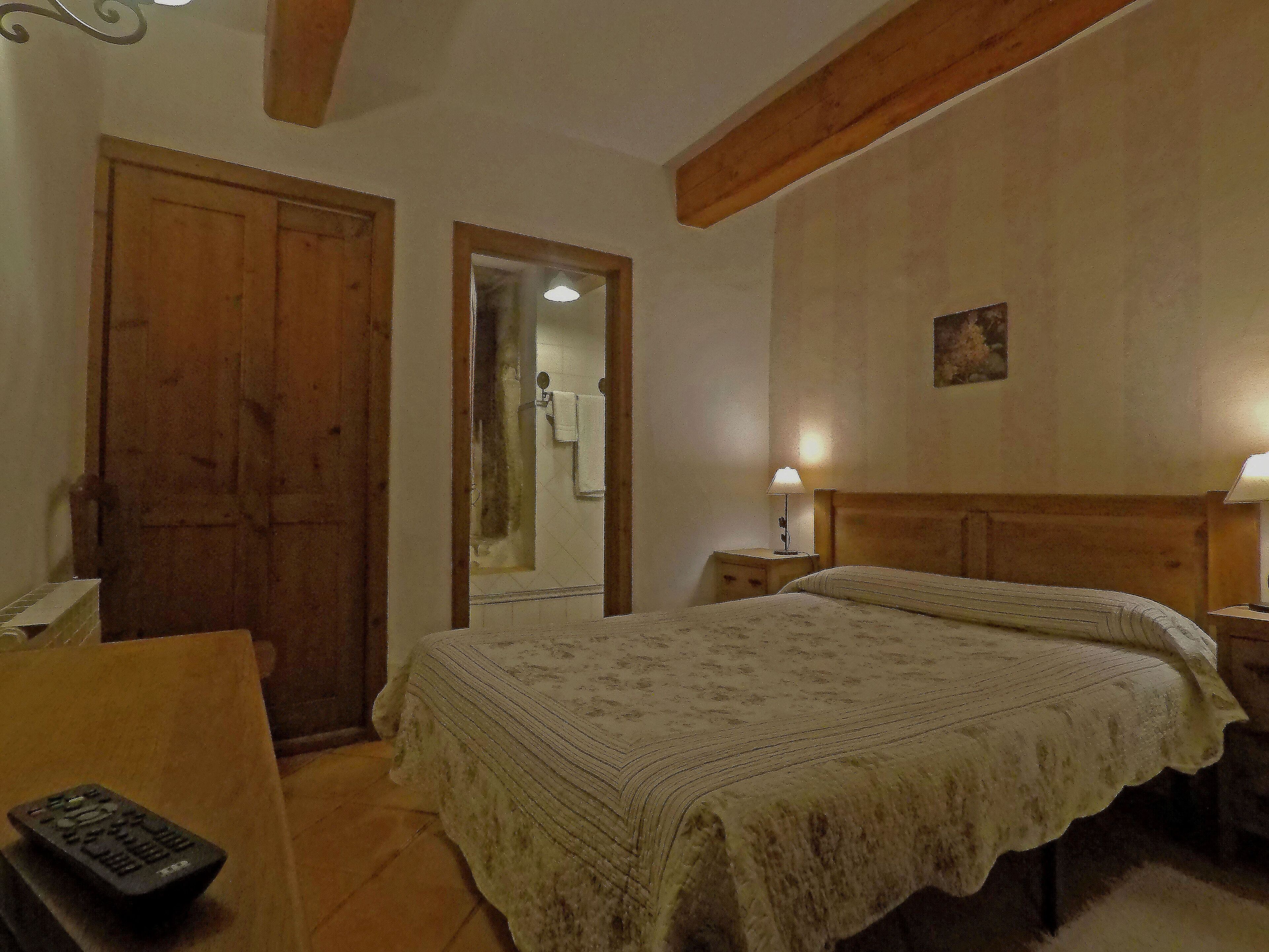 Une chambre à coucher avec un grand lit, une tête de lit en bois, une table de chevet avec une lampe, une porte en bois et un miroir.