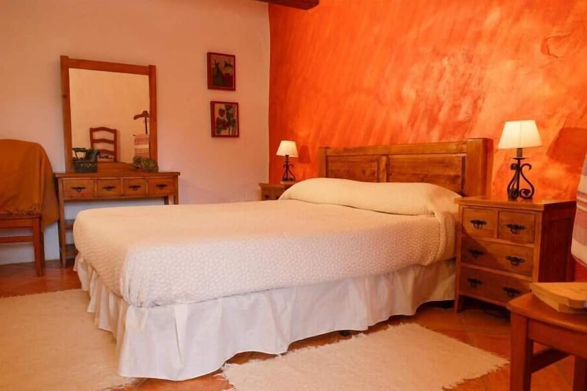 Um quarto com cama, penteadeira e mesas de cabeceira.