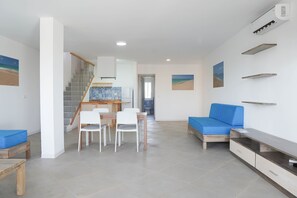 Una sala de estar moderna con una escalera, un comedor y un sofá.
