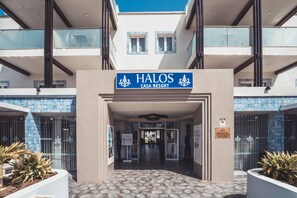 Welcome to Halos Casa Resort, where a clear pathway leads to the main entrance, flanked by lush greenery.