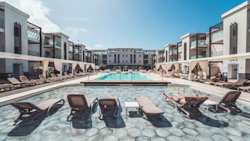 Una piscina al aire libre, sillones reclinables de piscina