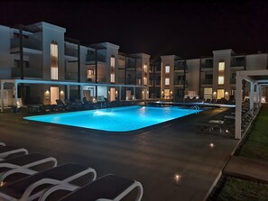 Relax by the pool surrounded by comfortable lounge chairs and umbrellas.