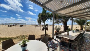 A beachside patio with a view of the beach, covered seating, and potted plants. - Halos Casa Resort (Sal)