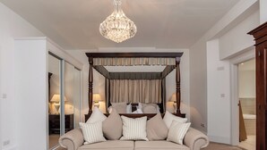 A bedroom with a four-poster bed, a beige sofa, and a tufted ottoman. - 1 bedroom accommodation in Torquay (Torquay)