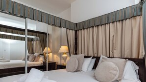 A hotel room with a large bed, two bedside tables, a mirror, and curtains. - 1 bedroom accommodation in Torquay (Torquay)