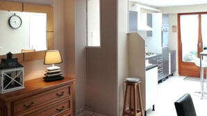 A room with a wooden dresser, a lamp, a clock, and a window.