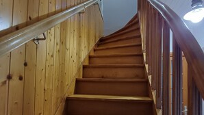 A wooden staircase with a handrail and a light fixture above.