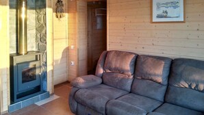 A cozy living room with a fireplace, a sofa, and a framed picture on the wall. - Comfortable cottage on a beautiful lake (Uro)